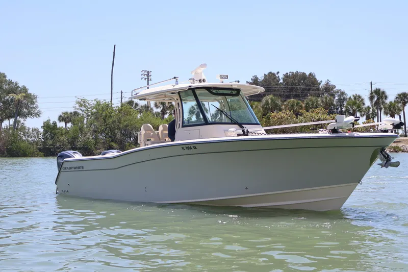 Slide: The Image of 2021 Grady-White Canyon 336 boat on calm water, surrounded by lush greenery. - 2
