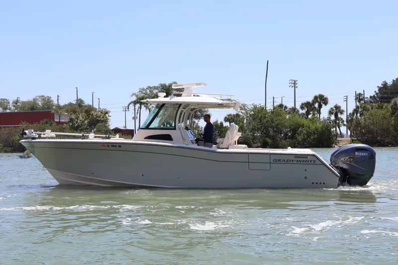 Slide: The Image of 2021 Grady-White Canyon 336 boat cruising on a sunny day with lush greenery background. - 8
