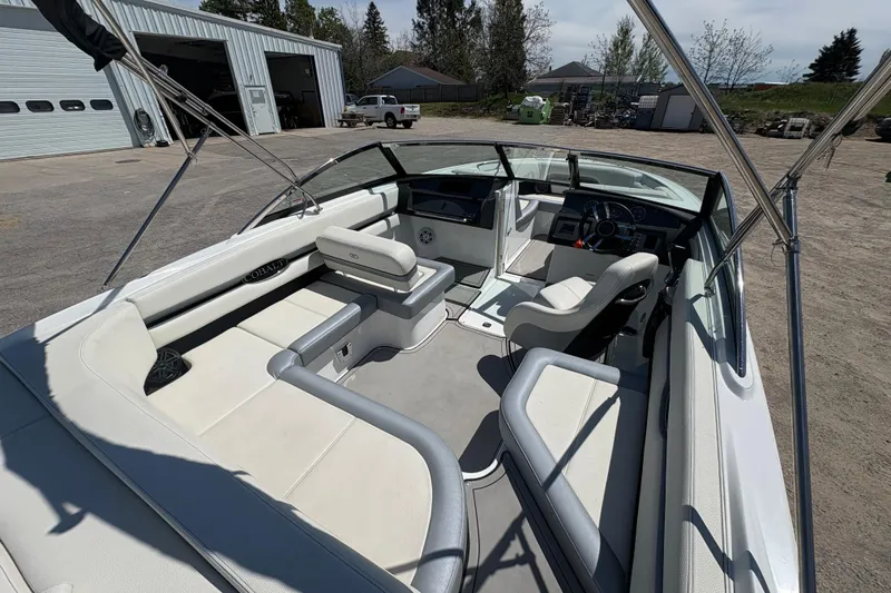 Slide: The Image of 2021 Cobalt CS23 boat interior with white seating and steering wheel, parked outdoors. - 8
