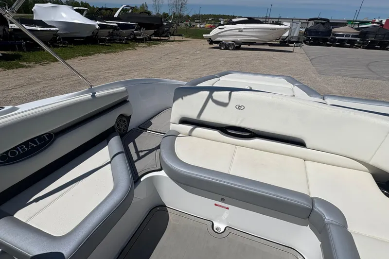 Slide: The Image of 2021 Cobalt CS23 boat interior with white seating, parked among other boats. - 9
