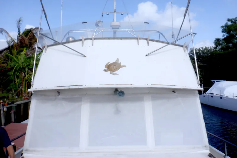 Slide: The Image of 1980 Grand Banks 49 Classic yacht with turtle emblem, docked near lush greenery. - 13