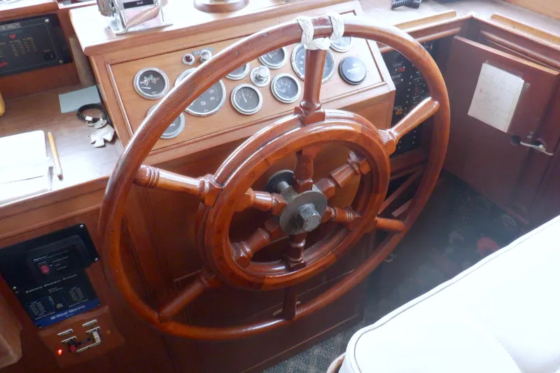 Slide: The Image of Wooden helm of a 1980 Grand Banks 49 Classic yacht, featuring classic gauges and controls. - 25
