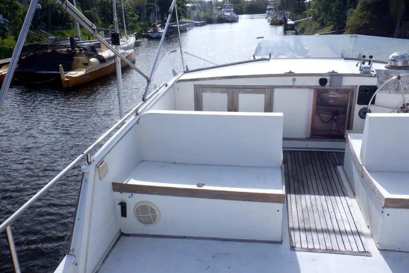 Slide: The Image of 1980 Grand Banks 49 Classic yacht deck with seating, docked on a calm river. - 3