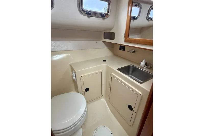 Slide: The Image of 2006 Albin 28 Tournament Express boat bathroom with sink, toilet, and storage cabinets. - 23
