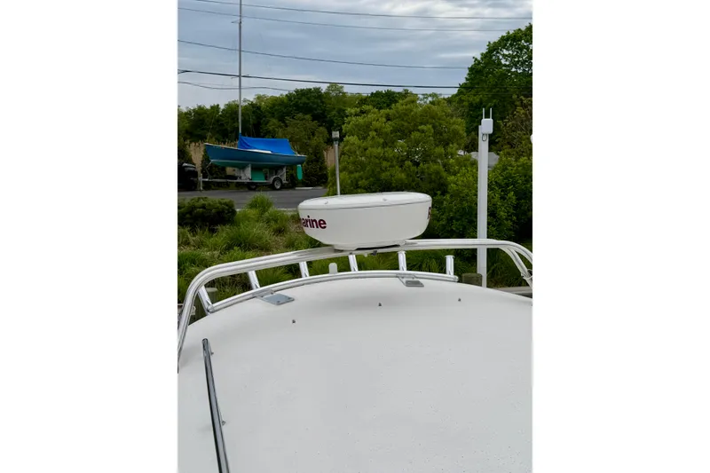 Slide: The Image of 2006 Albin 28 Tournament Express boat with radar, surrounded by greenery and a parked trailer. - 34