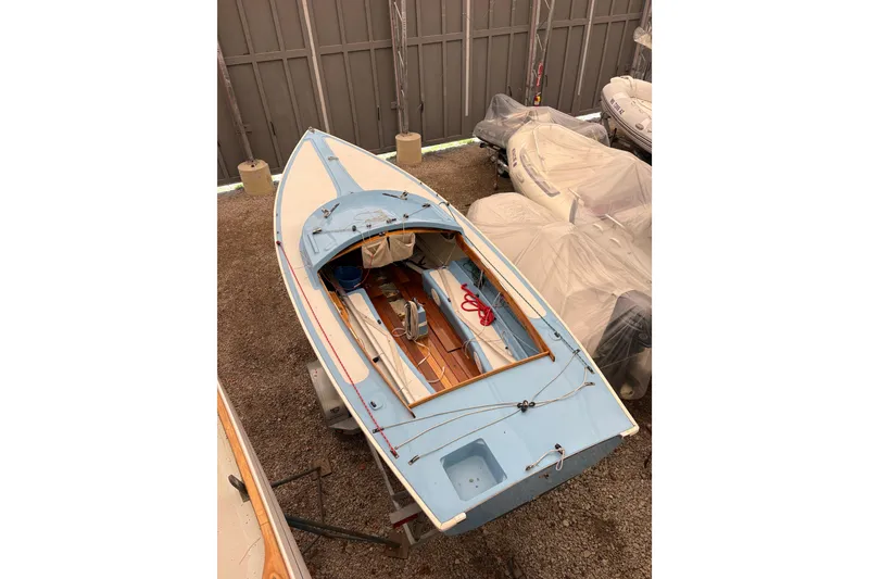 Slide: The Image of 1971 Rhodes 19 sailboat in storage, featuring a blue and white design. - 4