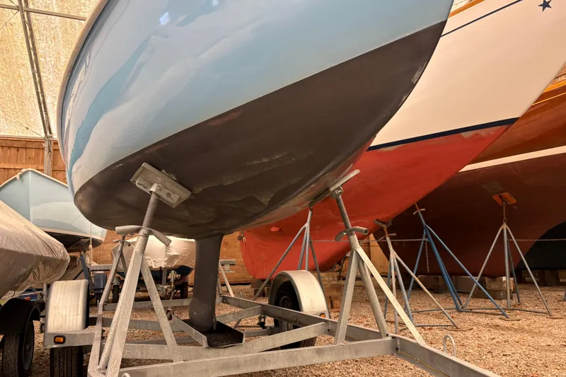 Slide: The Image of 1971 Rhodes 19 sailboat on trailer in storage, showcasing hull and keel. - 8