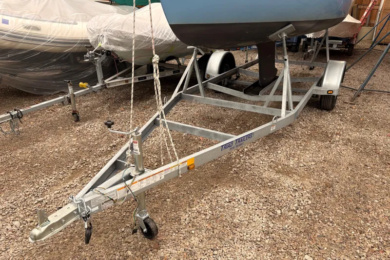Slide: The Image of Trailer holding a 1971 Rhodes 19 sailboat, parked on gravel. - 9