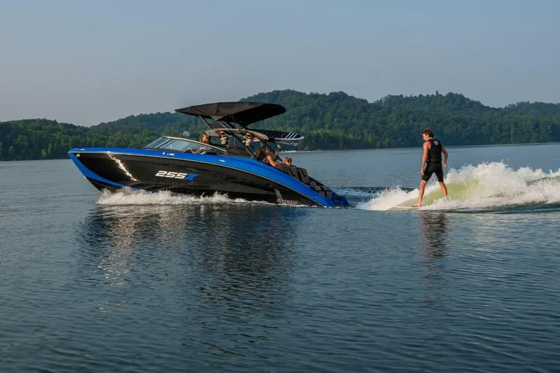Slide: The Image of 2026 Yamaha Boats 255XD on lake with wakeboarder, surrounded by scenic hills. - 5