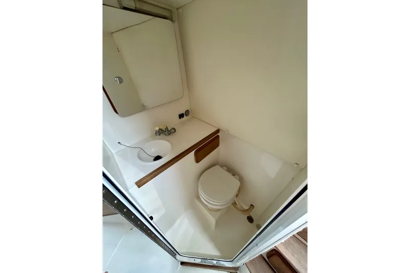 Slide: The Image of Compact bathroom in 2001 Contender 35 Side Console boat, featuring toilet and sink. - 16