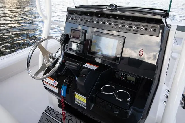 Slide: The Image of 2023 Wellcraft 222F boat dashboard with steering wheel, controls, and navigation screens. - 9