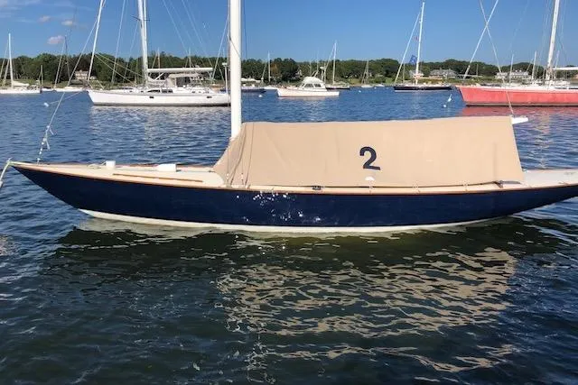 Slide: The Image of 1963 Cape Cod Shipbuilding Shields sailboat moored in a marina, covered with a beige tarp. - 1