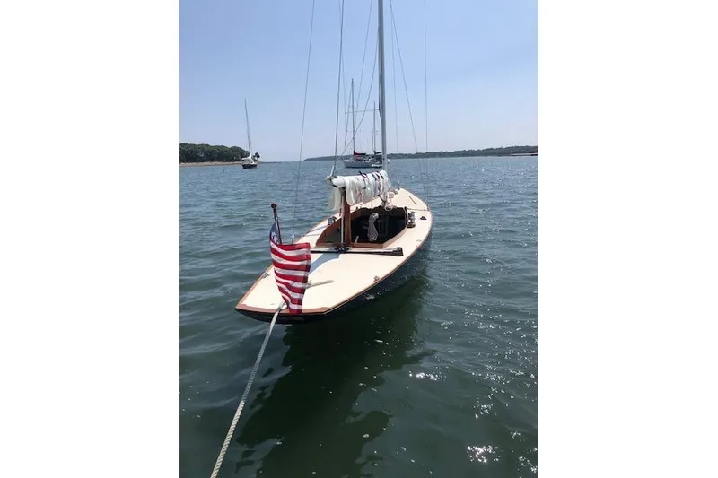Slide: The Image of 1963 Cape Cod Shipbuilding Shields sailboat with American flag on calm water. - 14