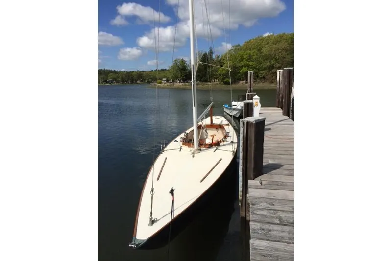Slide: The Image of 1963 Cape Cod Shipbuilding Shields sailboat docked on a serene lake under a blue sky. - 21