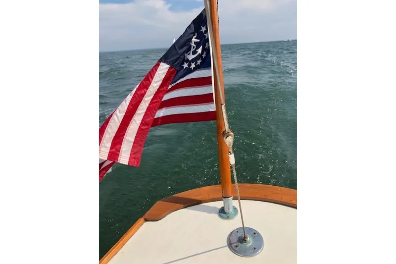 Slide: The Image of Sailboat with American flag on Cape Cod Shipbuilding Shields, 1963, sailing on open water. - 4