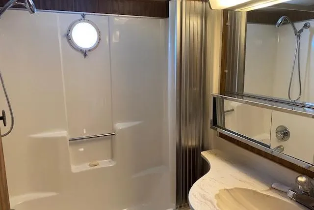 Slide: The Image of 1980 Lazy Days 14x59 bathroom with shower, porthole window, and mirrored vanity. - 10