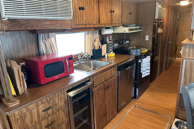 Slide: The Image of 1980 Lazy Days 14x59 kitchen with wood cabinets, red microwave, and modern appliances. - 4