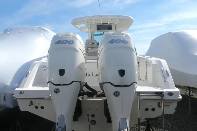 Slide: The Image of 2020 Boston Whaler 330 Outrage with twin 400 horsepower engines, docked under clear skies. - 1