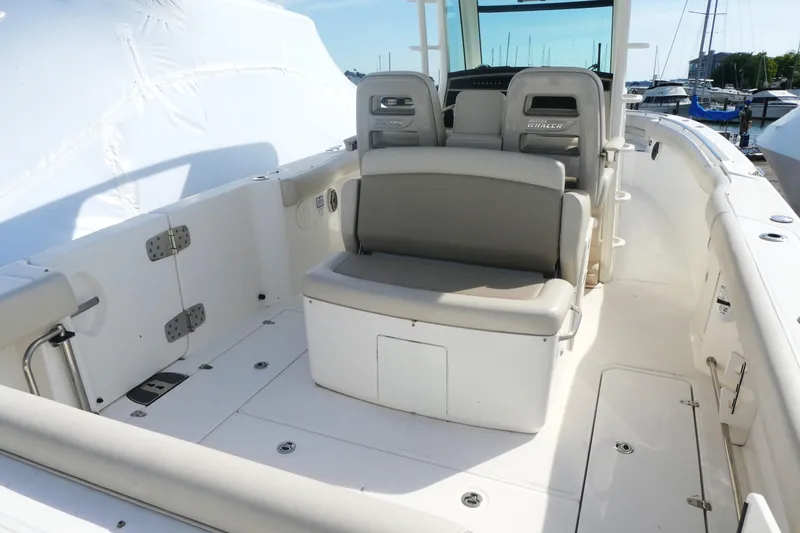 Slide: The Image of 2020 Boston Whaler 330 Outrage boat interior with seating and storage, docked at marina. - 2