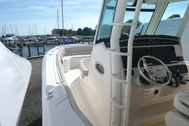 Slide: The Image of 2020 Boston Whaler 330 Outrage boat at marina, featuring helm and seating area. - 9
