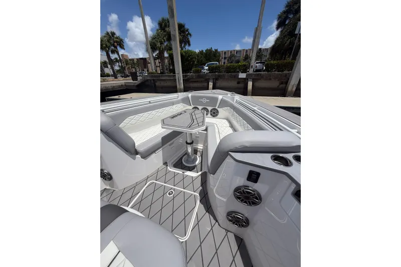 Slide: The Image of 2024 Fountain 38 SCX boat interior with seating, table, and speakers under a clear sky. - 11