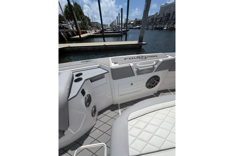 Slide: The Image of 2024 Fountain 38 SCX boat interior with seating and speaker, docked at marina. - 12