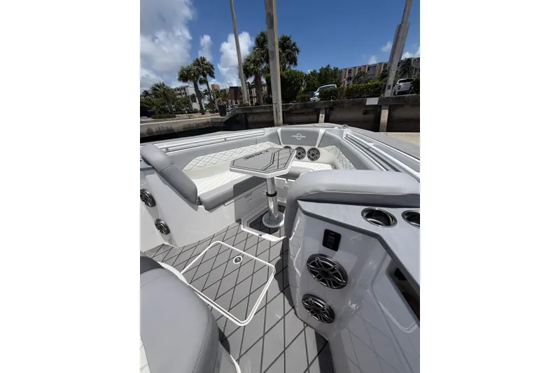 Slide: The Image of 2024 Fountain 38 SCX boat interior with seating, speakers, and table under a clear sky. - 14