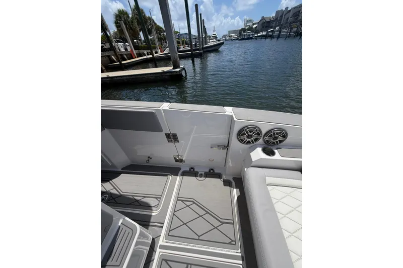 Slide: The Image of 2024 Fountain 38 SCX boat interior with speakers and seating at a marina. - 20