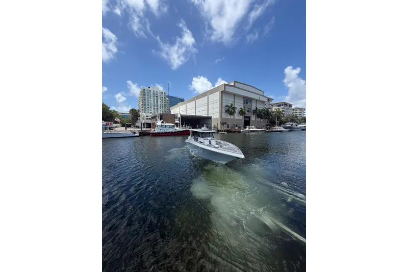 Slide: The Image of 2024 Fountain 38 SCX boat cruising in a marina with modern buildings and blue sky. - 35