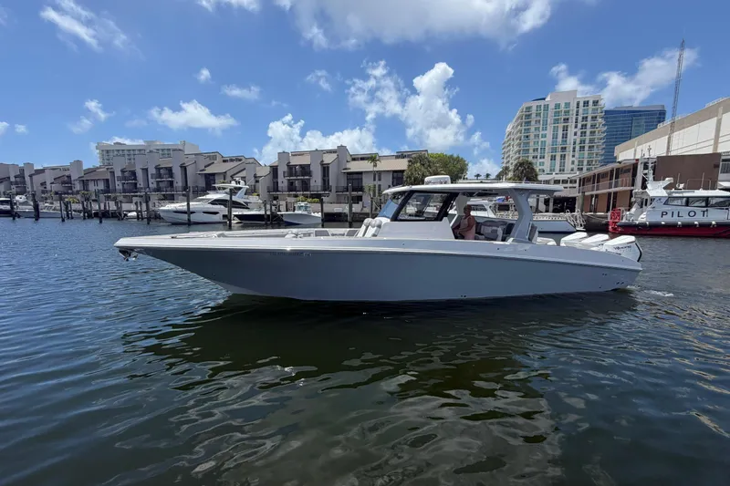 Slide: The Image of 2024 Fountain 38 SCX boat docked in a marina with modern buildings in the background. - 36