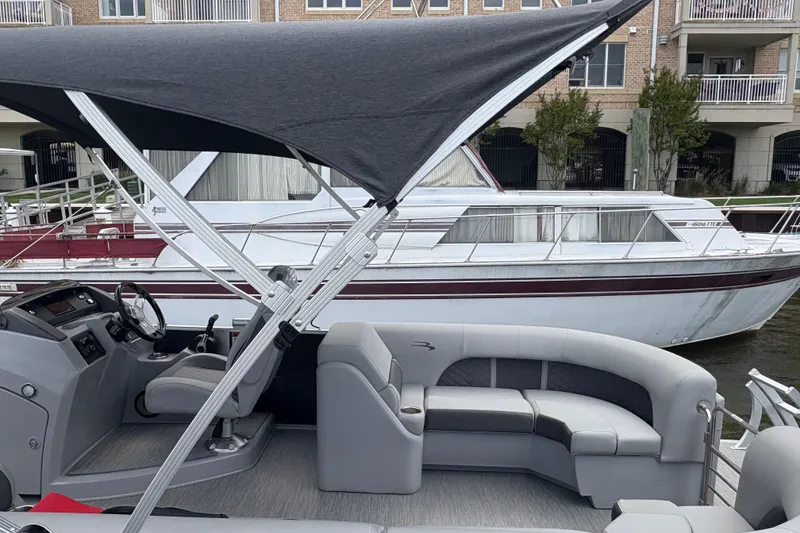 Slide: The Image of 2022 Bennington Saltwater Series boat with canopy and seating, docked near a larger vessel. - 3