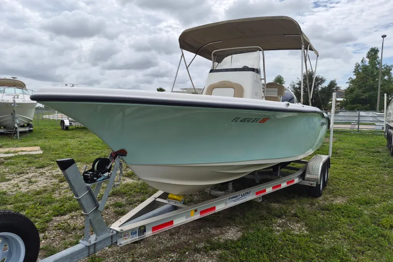 Slide: The Image of 2016 Key West 219 FS boat on trailer, parked on grassy area under cloudy sky. - 4