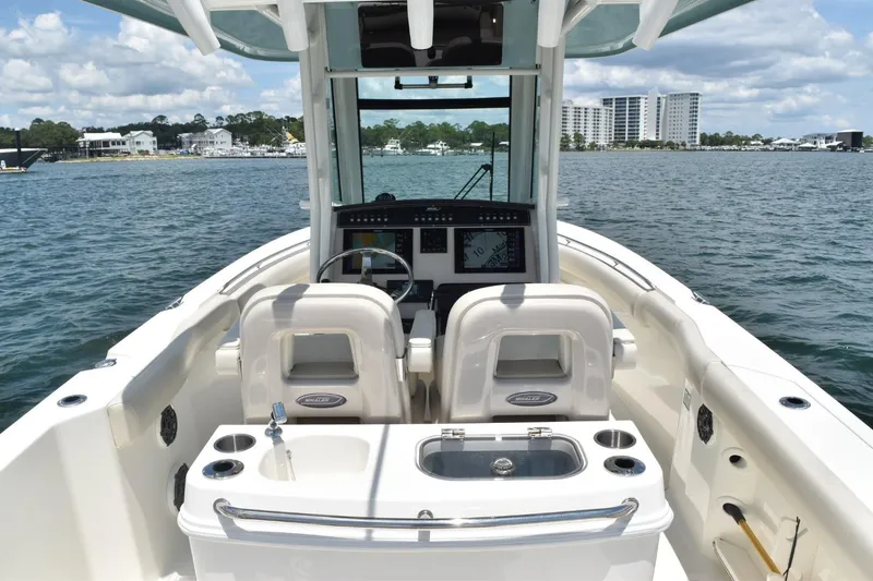 Slide: The Image of 2023 Boston Whaler 280 Outrage boat interior with helm and seating, on a scenic waterfront. - 12