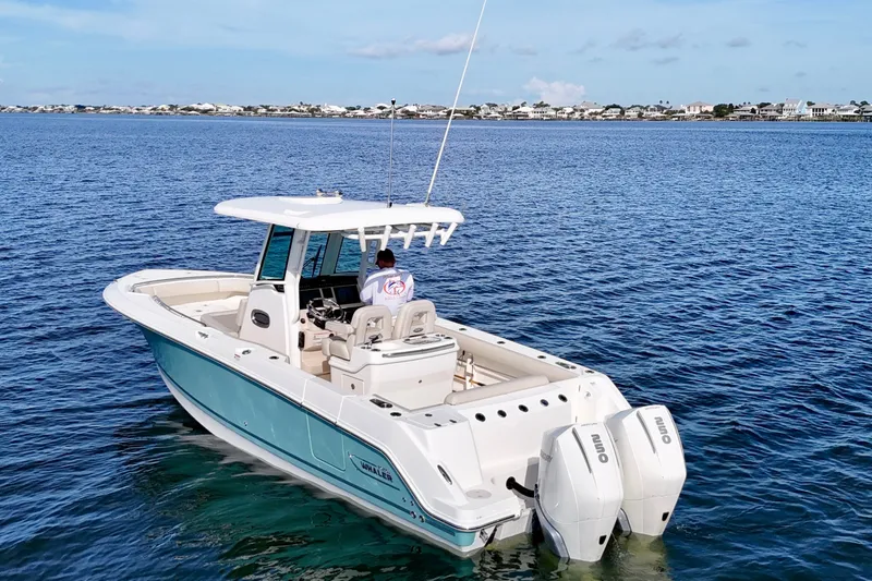 Slide: The Image of 2023 Boston Whaler 280 Outrage boat on calm blue water, coastal background. - 9