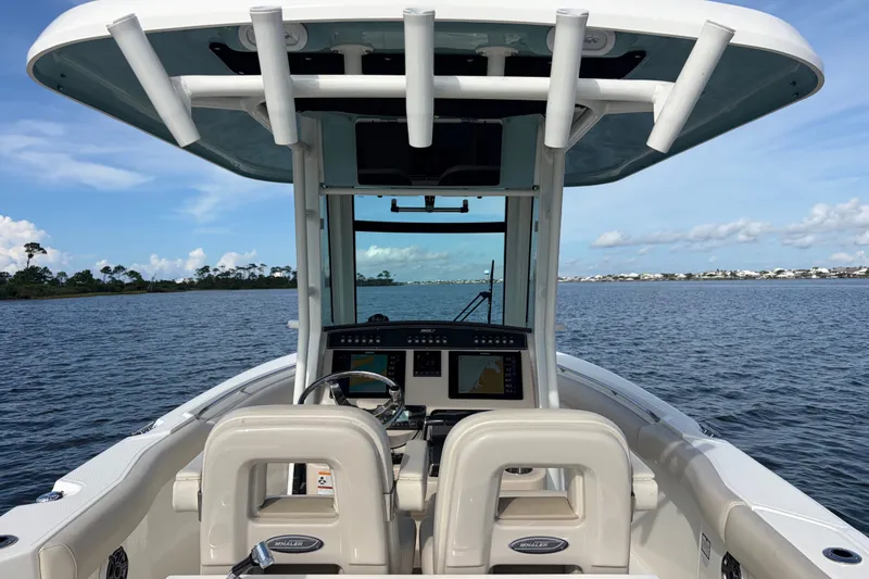 Slide: The Image of 2023 Boston Whaler 280 Outrage boat interior with helm, on calm waters under blue sky. - 15