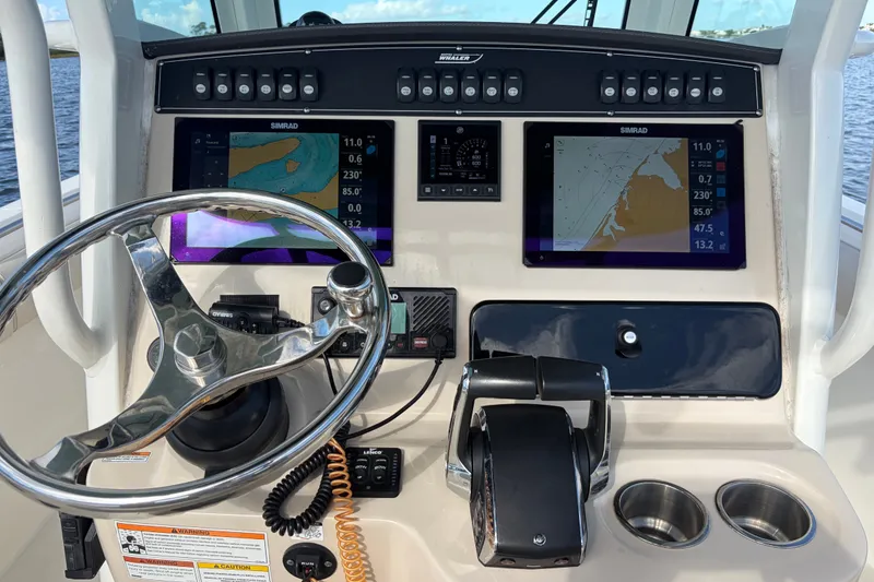 Slide: The Image of 2023 Boston Whaler 280 Outrage dashboard with navigation screens and steering wheel. - 16