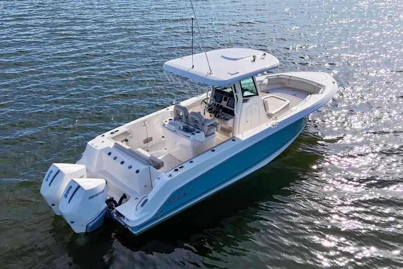 Slide: The Image of 2023 Boston Whaler 280 Outrage boat on shimmering water, showcasing sleek design and twin engines. - 5