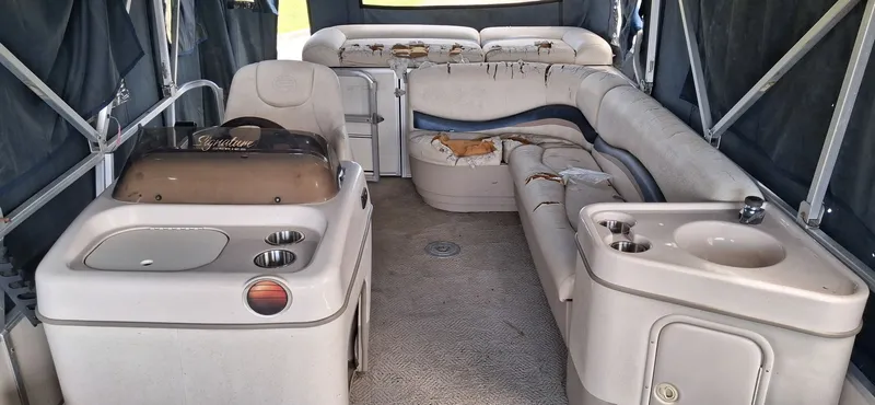 Slide: The Image of Interior of a 2006 Tracker 24 ft Pontoon boat with worn seating. - 2