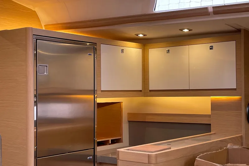 Slide: The Image of Modern interior of 2022 Dufour 530 yacht with sleek cabinetry and stainless steel fridge. - 21