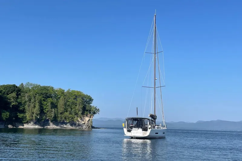 Slide: The Image of Sailboat Dufour 530 (2022) on calm water near a forested cliff. - 30