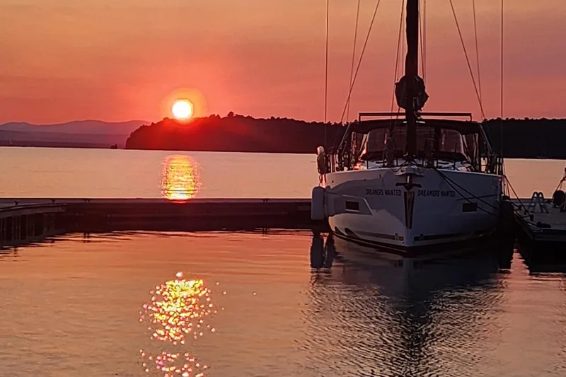 Slide: The Image of Sailboat Dufour 530 at sunset, reflecting on calm water, 2022 model. - 31