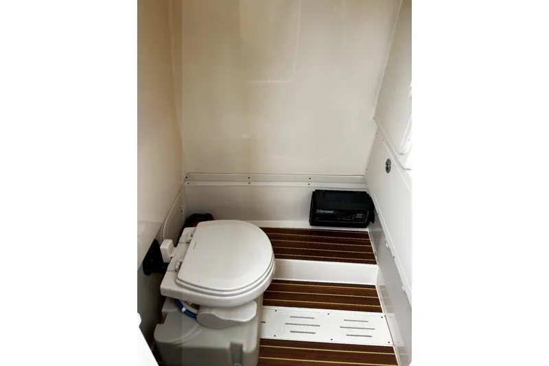 Slide: The Image of 2019 Scout 255 LXF boat interior with compact marine toilet and wooden flooring. - 10