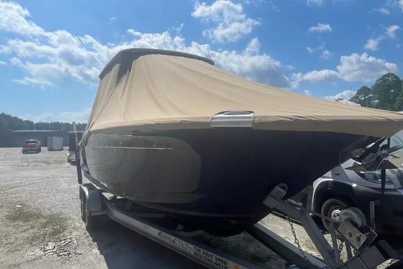 Slide: The Image of 2019 Scout 255 LXF boat covered on a trailer under a blue sky. - 17