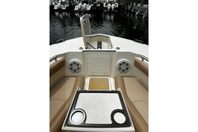 Slide: The Image of 2019 Scout 255 LXF boat interior with seating and speakers at a marina. - 7
