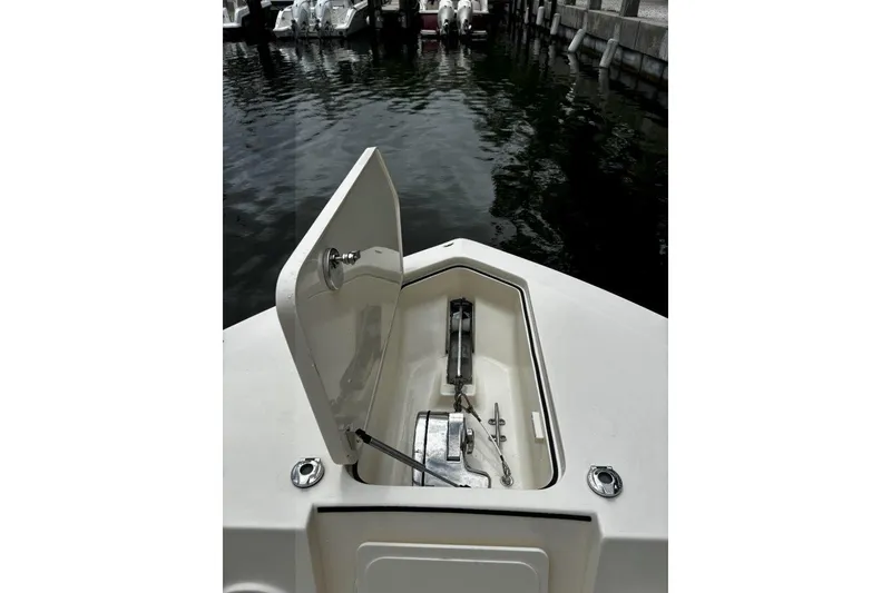 Slide: The Image of 2019 Scout 255 LXF boat with open anchor hatch, docked by the water. - 8