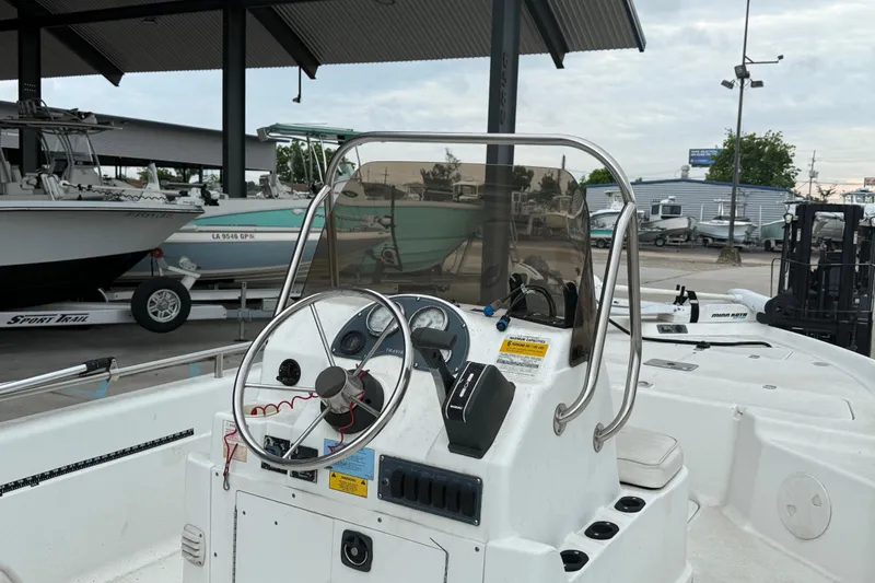 Slide: The Image of 2002 Fishmaster 19 boat dashboard with steering wheel and controls in a marina setting. - 13