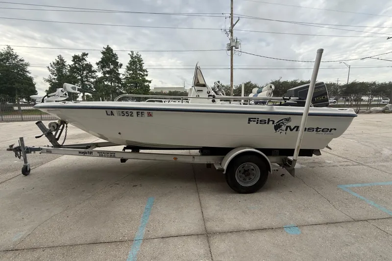 Slide: The Image of 2002 Fishmaster 19 boat on trailer, parked outdoors, featuring Suzuki engine. - 7