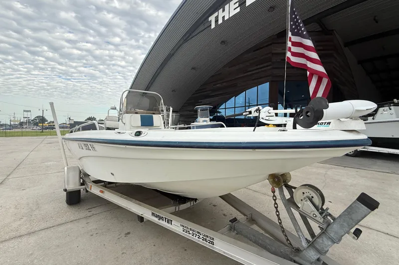 Slide: The Image of 2002 Fishmaster 19 boat on trailer with American flag, parked outside a building. - 9