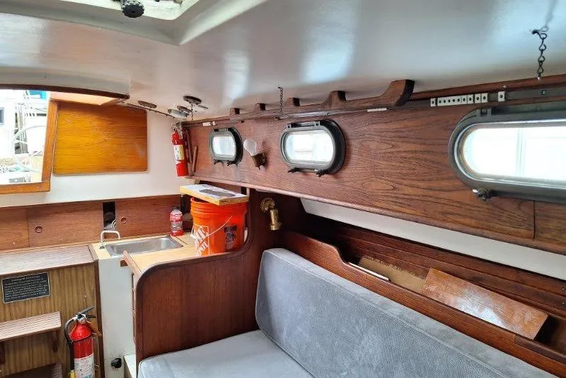 Slide: The Image of Interior of a 1976 Cape Dory 30 sailboat, featuring wood paneling and portholes. - 9