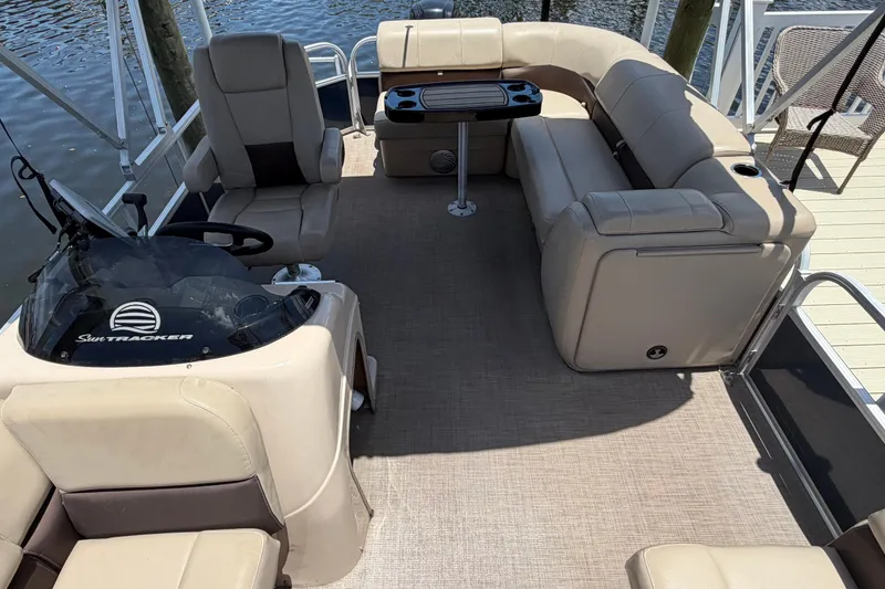 Slide: The Image of 2019 Sun Tracker Party Barge 20 DLX interior with beige seating and steering console. - 16